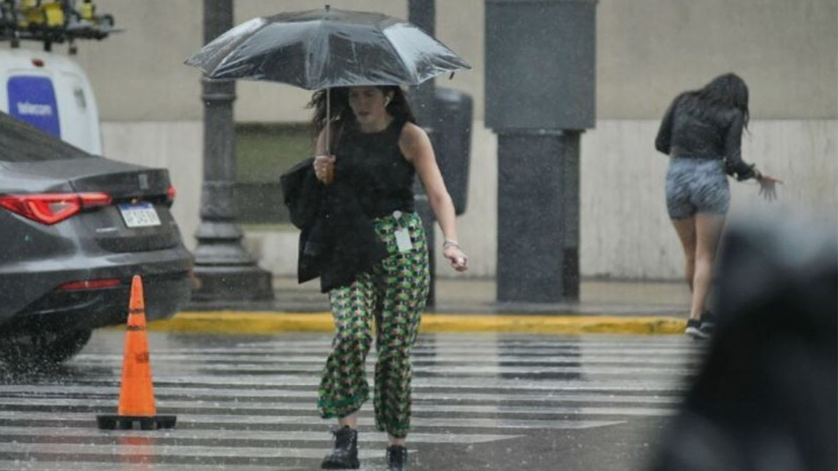 Mujer cruza la calle con un paraguas durante la lluvia en Buenos Aires